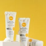 Close-up of sunscreen tubes displayed on white blocks against a yellow background, ideal for skincare promotions.