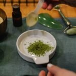 A person blends herbal powder for skincare treatment indoors.